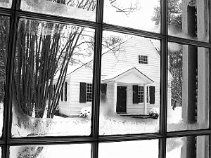 View of old Meetinghouse covered in snow as seen through window of brick Meetinghouse